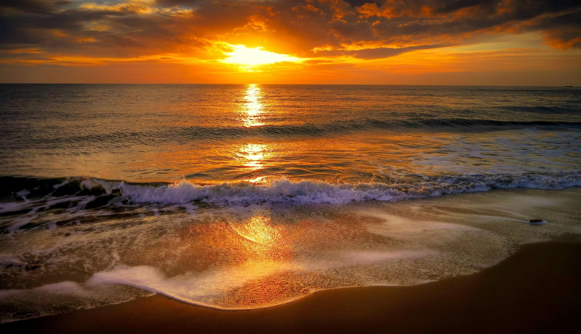 Capture the beauty of a vibrant beach sunset with gentle waves and a golden sky.