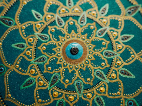 Detailed mandala artwork featuring gold and teal patterns, showcasing symmetry and creativity.